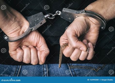 Handcuffed Hands Of A Prisoner Behind The Bars Of A Prison Royalty Free