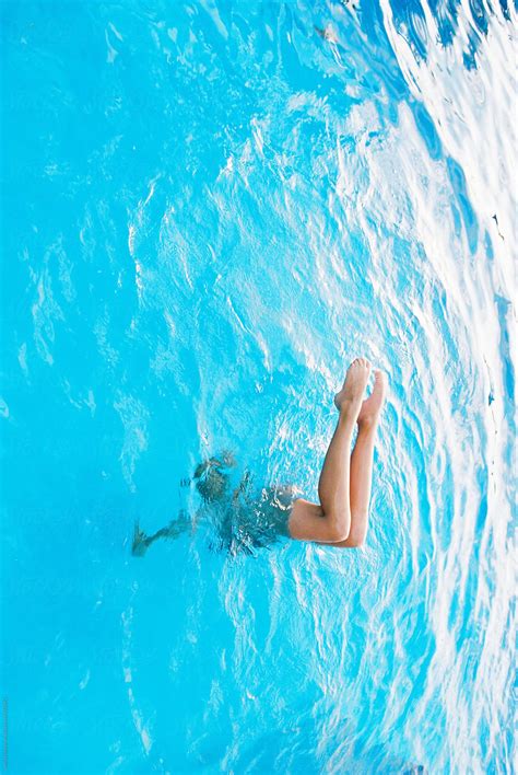 teen doing handstand with bent legs in swimming pool by stocksy contributor wendy laurel