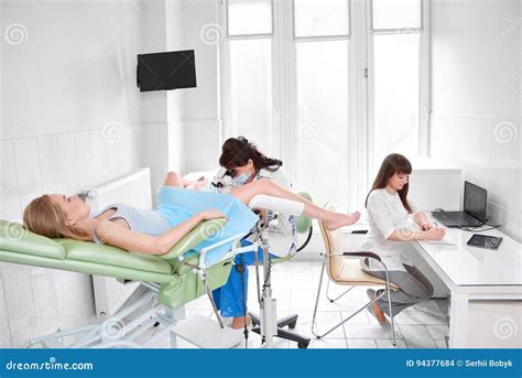 professional gynecologist examining her female patient on a gynecological chair royalty free