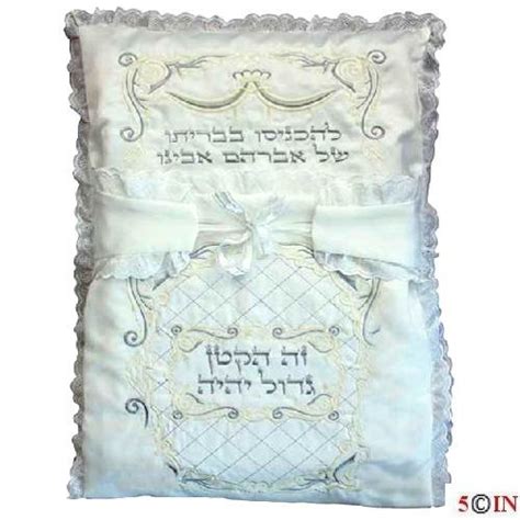 This white brit pillow is embroidered with silver colored floral patterns and hebrew text and has lace on the outer. Bris Milah Pillow Case