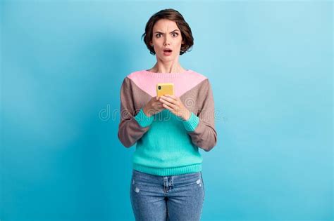 photo portrait of upset woman holding phone in two hands isolated on pastel light blue colored