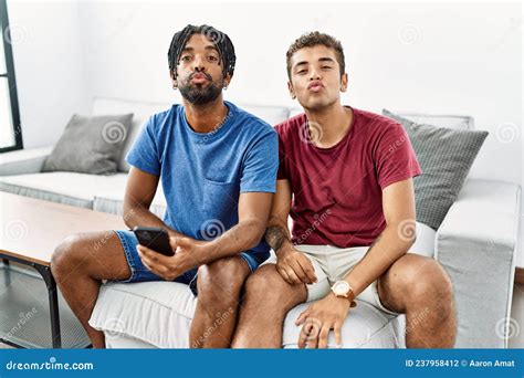 Young Hispanic Men Using Smartphone Sitting On The Sofa At Home Looking