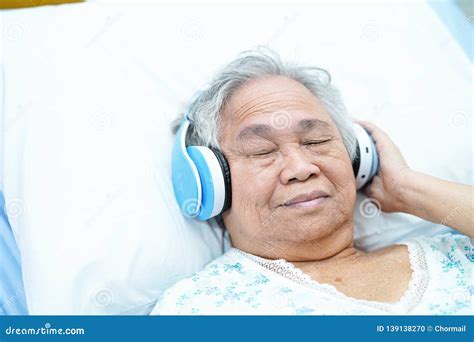 Asian Senior Or Elderly Old Lady Woman Patient Listen To Music While Lie Down On Bed In Nursing