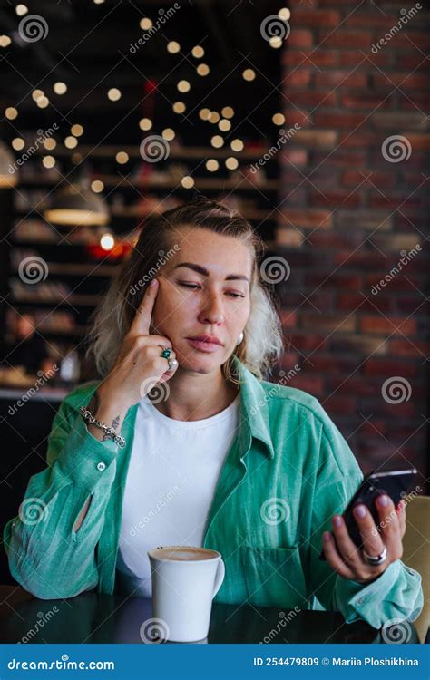 Beautiful Stylish Woman In Green Shirt Sitting In Loft Cafe Drinking Cappuccino And Checking