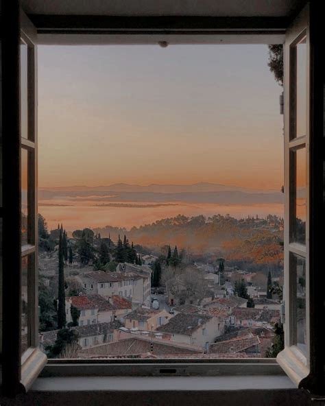 An Open Window With The View Of A Town And Mountains In The Distance At