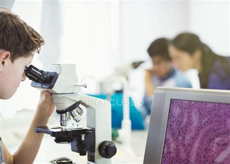 Boy Student Using Microscope Conducting Scientific Experiment In