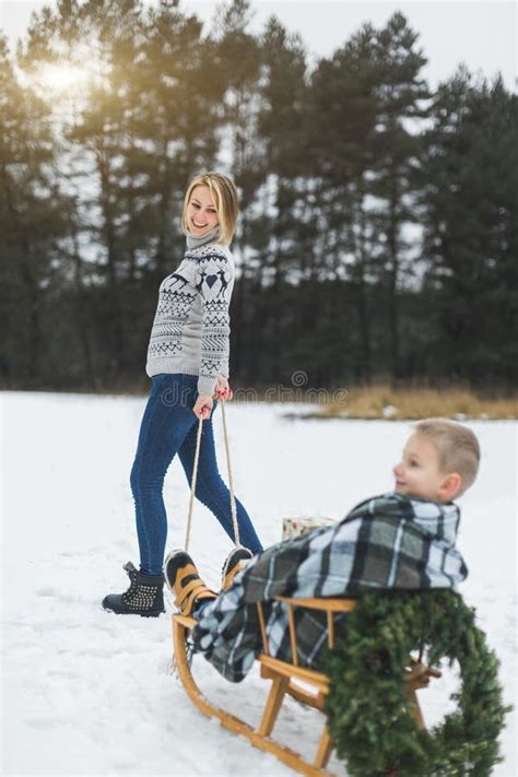 Pretty Young Mother Pulling Decorated Wooden Sled With Her Son Sitting
