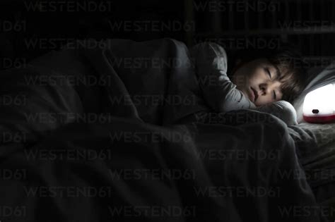 Girl Sleeping In Bed At Night With Night Light Stock Photo