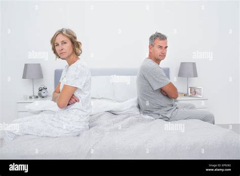 Couple Sitting On Different Sides Of Bed Not Talking After Argument