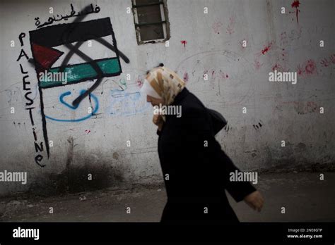 A Palestinian Woman Walks Past A Graffiti Of A Palestinian Flag And A