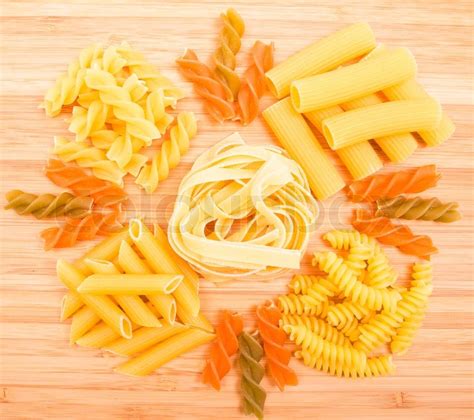 Different Kinds Of Italian Pasta On Wooden Background Stock Photo