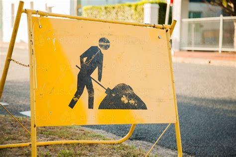 Image Of Yellow Digging Road Work Sign Near Construction Site On