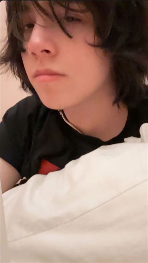 A Close Up Of A Person Laying In Bed With A White Pillow And Black Shirt