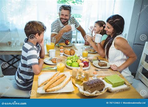 Familia Feliz Que Habla El Uno Al Otro Mientras Que Desayunando Junto