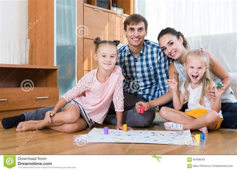 Girls Playing With Parents At Board Game On Floor Stock