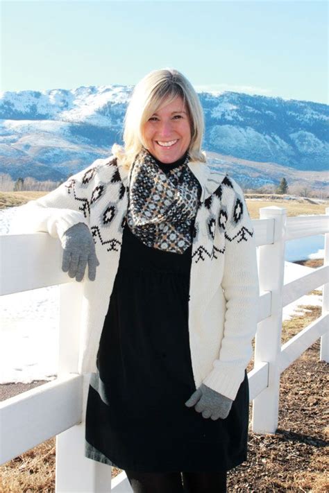 A Woman Standing In Front Of A White Fence With Mountains In The Backgroud