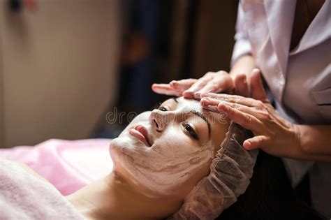 Woman Getting Facial Care Peeling Mask By Beautician At Spa Salo Stock
