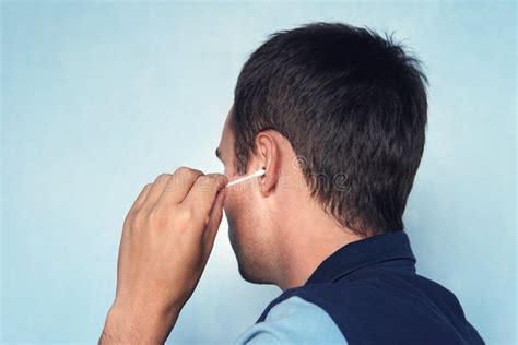 Man Cleaning Ear With Cotton Bud On Blue Background Stock Image