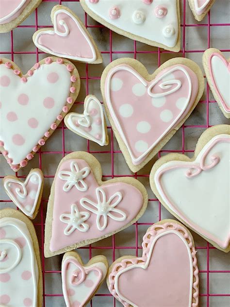Decorated Cookies On A Wire Rack With Pink And White Icing In The Shape