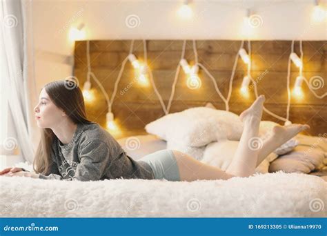 muchacha con largas piernas desnudas sobre la cama foto de fondo de la ventana imagen de archivo