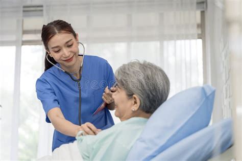 Nurse Or Doctor Is Caring For An Elderly Female Patient Lying On The