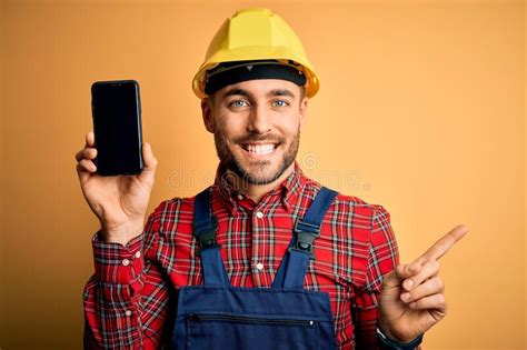 Young Builder Man Wearing Safety Helmet Showing Smartphone Screen Over
