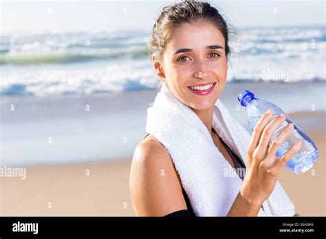 Pretty Healthy Woman Drinking Water After Exercise On Beach Stock Photo