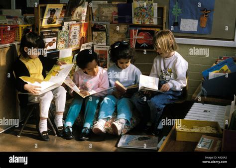 A Group Of Children Quietly Reading In The Book Corner Of The Classroom