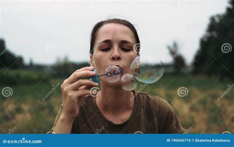 The Girl Blows Soap Bubbles A Young Woman Sits In Nature And Blows