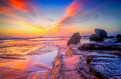 Panaroma Photo Of Body Of Water Near Rock Formation Under Golden Hour