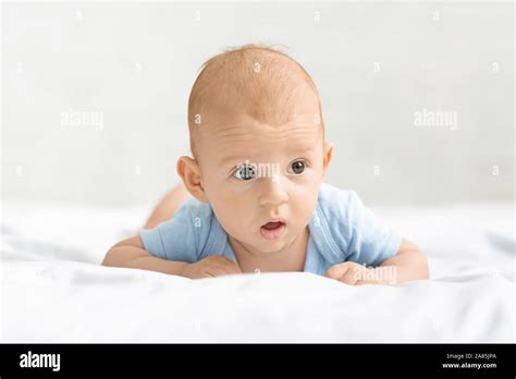 Portrait Of Funny Newborn Baby Lying On Tummy In Bed Stock Photo Alamy