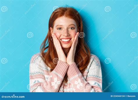 Close Up Of Cheerful Redhead Girl Blushing Touching Cheeks And Smiling