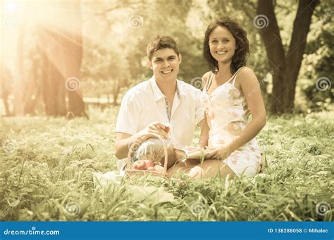 Beautiful Couple Sitting In The Grass Looking Into The Camera Smiling