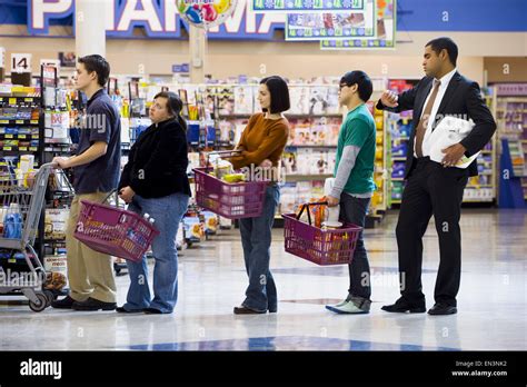 People Waiting In Line With Shopping Baskets At Grocery Store Stock