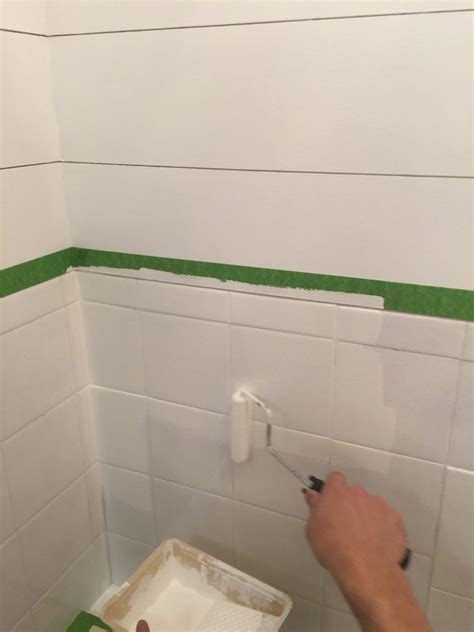 A Person Using A Paint Roller To Paint The Walls In A Bathroom With