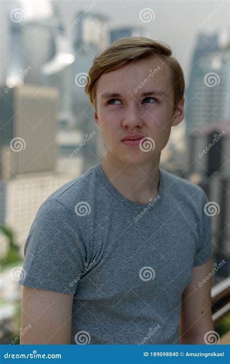 Young Handsome Blond Teenage Boy Thinking Against View Of The City