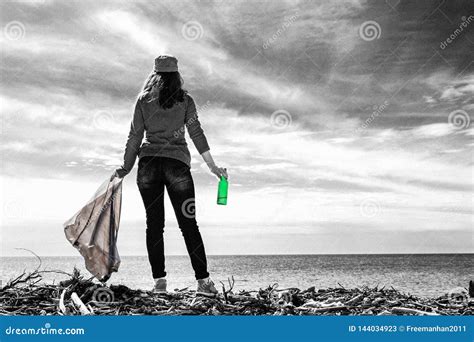 A Young Woman Stands With Her Back Turned With A Garbage Bag And A