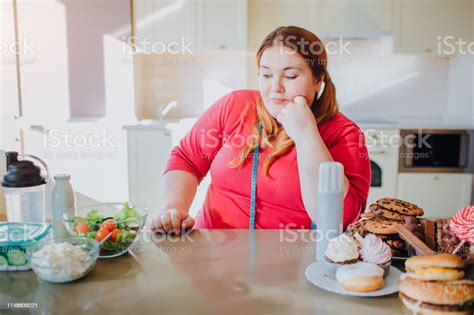 Fat Young Woman In Kitchen Sitting And Eating Food She Look At Healthy