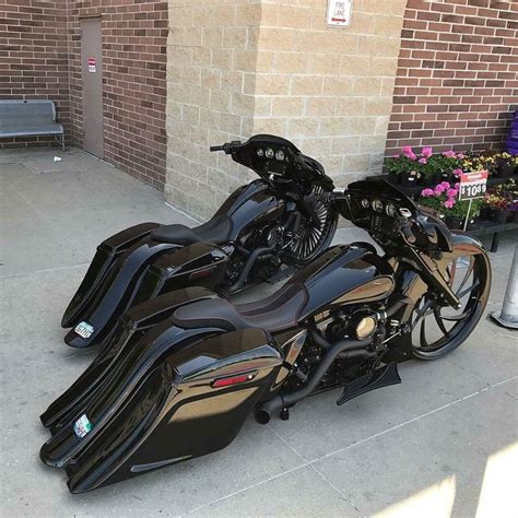 A Black Motorcycle Parked On The Side Of A Street Next To A Brick