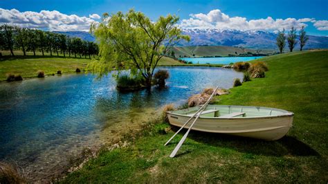 White Boat On Green Grass Near With Landscape Of Trees Under Blue Sky