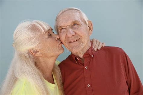 Blonde Mature Woman Kisses Loving Partner Standing On Light Grey Background Stock Image Image