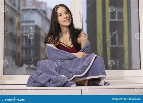 Charming Brunette Woman Wrapped In Blue Blanket Sitting On Windowsill
