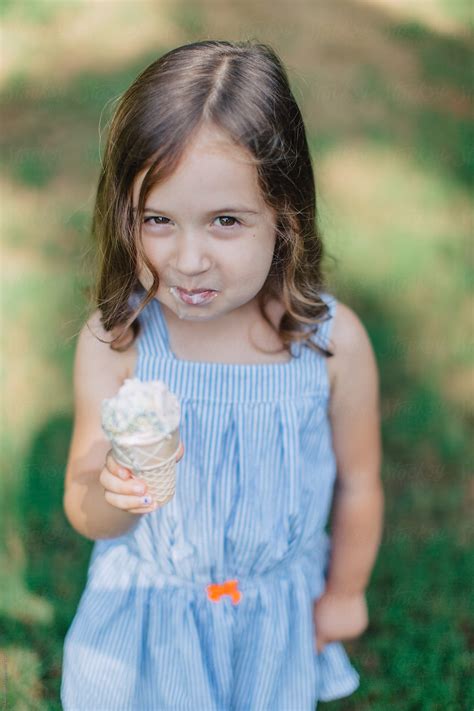 Cute And Happy Young Girl Eating Ice Cream Outside By Stocksy