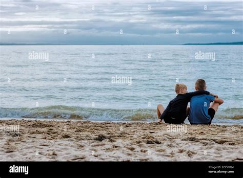 Two Brothers Bond Over The Beauty Of The Ocean As They Sit On The Beach