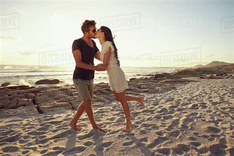 Portrait Of Romantic Caucasian Couple In Love On The Beach Kissing At