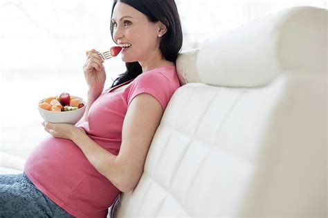 Pregnant Woman On Sofa Eating Fresh Fruit Photograph By Ian Hooton