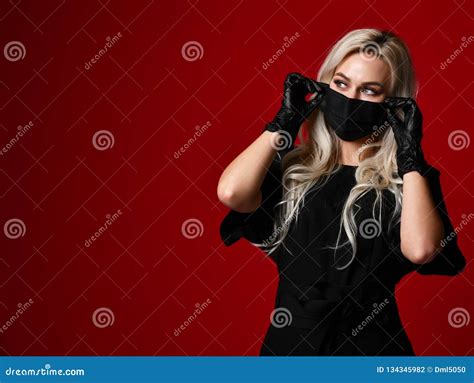 Beautiful Woman In Protective Black Medical Mask And Gloves On Dark Red