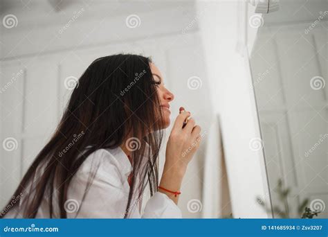 Beautiful Caucasian Woman Applying Makeup At Bright Room Stock Photo