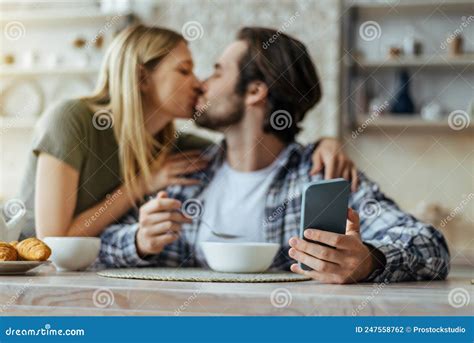 Happy Caucasian Millennial Blonde Wife Kisses Husband With Stubble Guy Have Lunch Holds