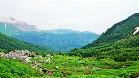 Mountain Valley Green Grass White Stones And Clouds Stock Photo